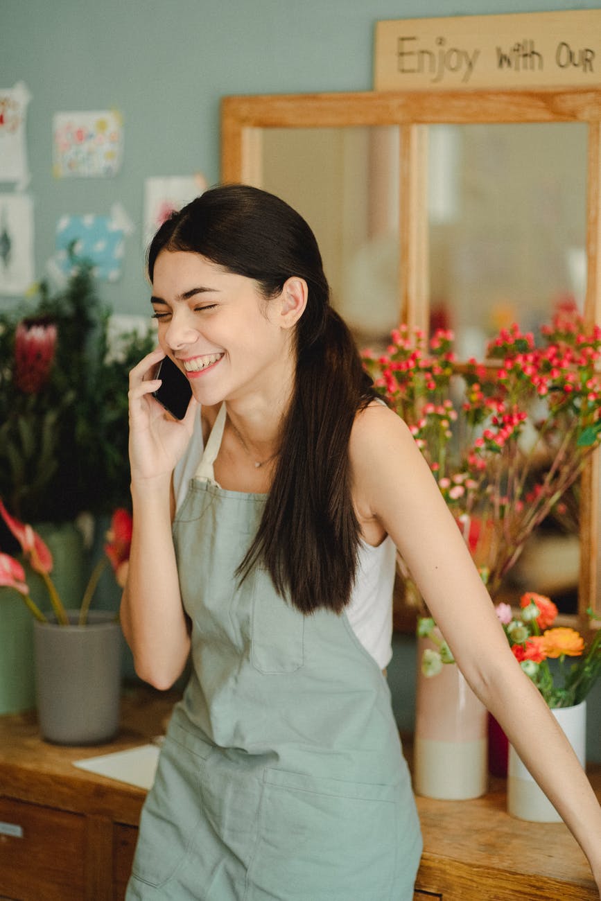 smiling woman speaking on phone in floral store